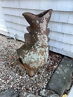 Left side profile of fish-shaped terracotta chiminea showing lichen and feet