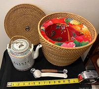 Teapot, rattan basket with lid, scoop, brush, tape measure for scale
