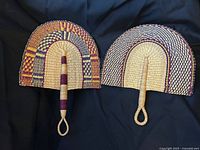 Two woven straw fans side by side showing patterns and handles