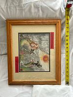 Front view of framed dragon artwork with tape for scale