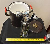 Open ice bucket, lid, tumbler with tools, measuring tape for scale