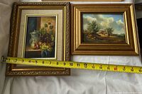 Both framed paintings side by side with tape measure