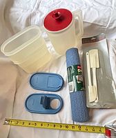 Group shot of all items: pitcher, two containers with lids, grip liner roll, spatula pack, measuring tape for scale