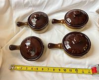 Top view of four lidded crocks next to tape measure