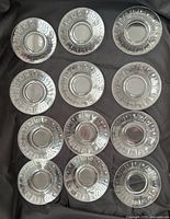 All twelve clear pressed glass plates laid out