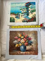 Both unframed oil paintings side by side with tape measure for scale