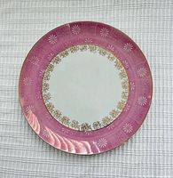 Front of porcelain plate showing pink rim, gold floral band, white center