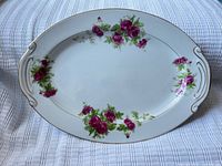 Full view of oval porcelain platter showing handles, rose pattern, gold rim