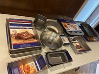 Overview of assorted baking pans on table, many still packaged