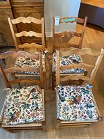 Four wooden ladder-back chairs with cushions displayed together