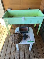 Overall view of metal planter, plastic table with ceramic pot, stones, wicker basket