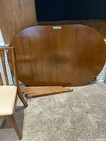 Table top propped upright with legs and one chair visible