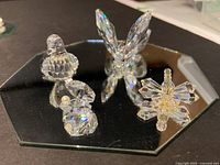 Four crystal pieces on hexagonal mirror: bird, abstract swirl, starburst ornament, upright wing/leaf form