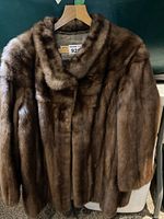 Front view of brown fur coat on hanger