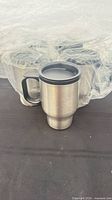 Front view of one stainless steel travel mug, others in plastic wrapping behind