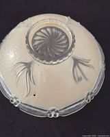 Top view of frosted glass shade showing floral rim and center mounting hole