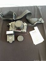 Top-down view showing Ricoh camera with lens, strap, flash, spare cap and receipt