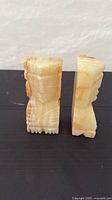 Front angled view of both carved onyx head bookends showing color and carving detail