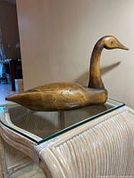 Left side view of hand-carved wooden Canada Goose decoy on glass table