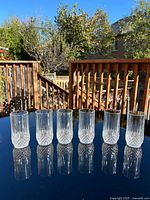 Six crystal tumblers on reflective surface, full view
