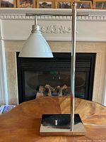 Front view of chrome table lamp with glass shade on wood surface