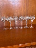 Front view of six Ajka Csopak Pinwheel hock wine glasses on shelf