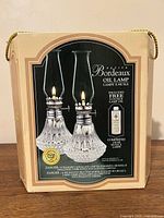 Front of retail box showing Petite Bordeaux oil lamps and included oil