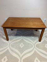 Full view of rectangular teak coffee table on rug