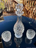 Decanter with stopper between two tumblers