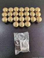 25 brass knobs arranged in rows with hardware bag