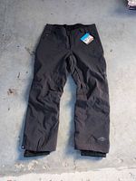 Full view of black Columbia snow pants laid flat