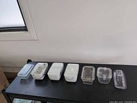 Seven storage dishes lined up, showing mix of glass and ceramic bases with lids