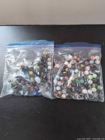 Two zipper bags filled with assorted glass marbles placed side by side
