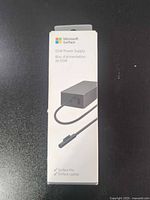 Front of sealed Microsoft Surface 65W Power Supply retail box