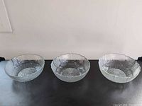 Front view of three identical clear pressed glass bowls