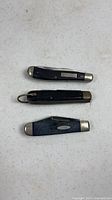 Three closed folding pocket knives stacked
