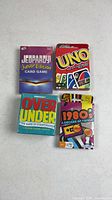 Front view of four boxed card games: Jeopardy! Junior Edition, Uno, Over Under (sealed), 1980s Trivia