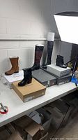Overview of five boxed pairs of women’s shoes/boots on table