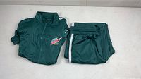 Dark green Mountain Dew Baja Blast track jacket folded alongside matching pants with white stripes