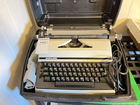 Typewriter placed inside hard case with power cord visible