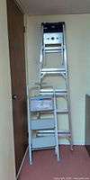 Both aluminum ladders standing against wall