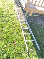 Full view of ladder extended on grass beside deck