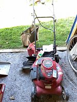 Full view of Craftsman red push mower with handle, bag, gas can nearby