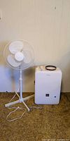 Danby dehumidifier and white pedestal fan side by side