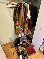 Closet view of poncho, sweater, jacket, blazer, shoes, belt, hair dryer, jewellery box, purses and hangers