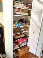full shelving unit showing cookbooks, kitchen linens, glass boards, wraps