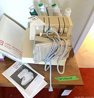 Serger with manuals, foot pedal and paperwork on table