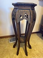 Full view of carved wooden plant stand front angle