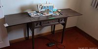 Full view of sewing cabinet open with sewing machine and foot pedal visible