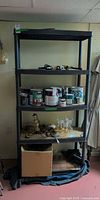 Full view of black plastic shelving unit with five shelves, contents present but not included